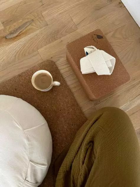 A meditation cushion, blanket and a cup of tea on a timber floor